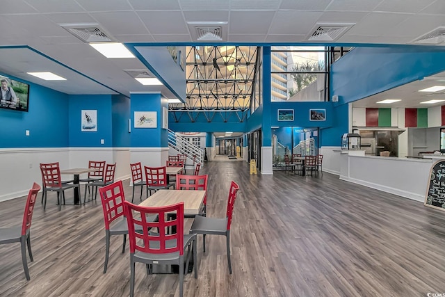 dining area featuring visible vents, a drop ceiling, and wood finished floors