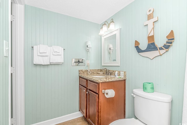 half bathroom with toilet, baseboards, and vanity