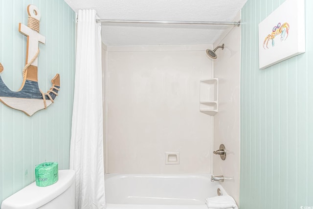 bathroom with toilet, shower / bath combo with shower curtain, and a textured ceiling