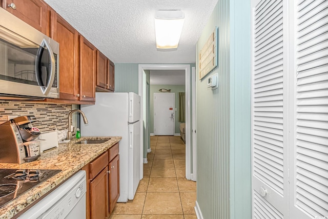 kitchen featuring light tile patterned floors, stainless steel microwave, brown cabinets, and backsplash