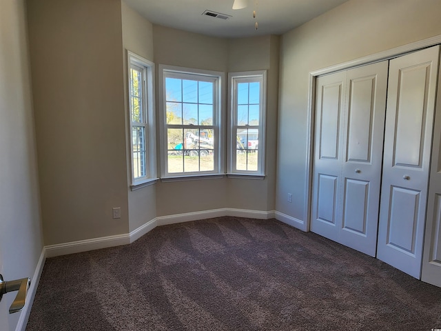 unfurnished bedroom with a closet and dark colored carpet