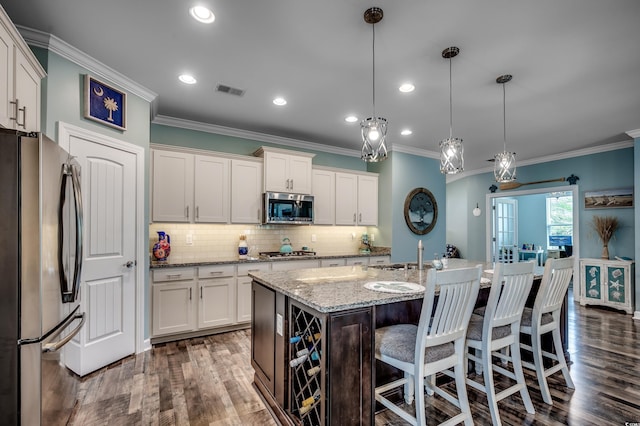 kitchen with white cabinetry, hanging light fixtures, dark hardwood / wood-style flooring, an island with sink, and appliances with stainless steel finishes