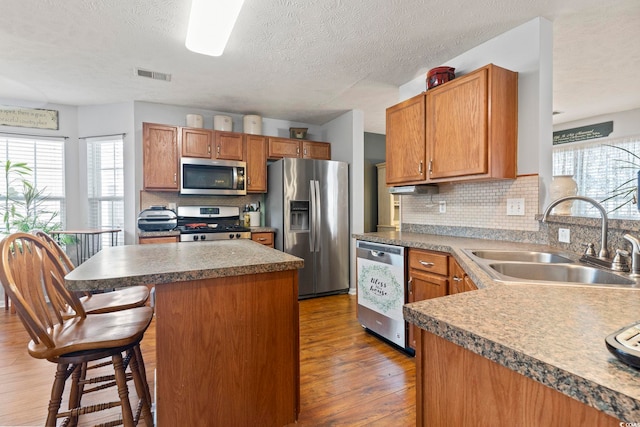 kitchen featuring sink, decorative backsplash, wood-type flooring, and stainless steel appliances