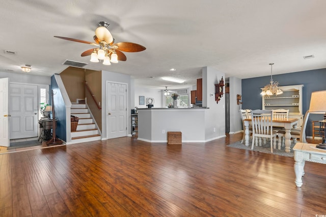 unfurnished living room featuring ceiling fan with notable chandelier and dark hardwood / wood-style flooring