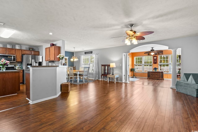 living room featuring ornate columns, ceiling fan, dark hardwood / wood-style floors, and a textured ceiling