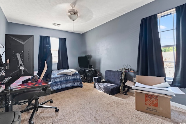 carpeted bedroom featuring ceiling fan and a textured ceiling