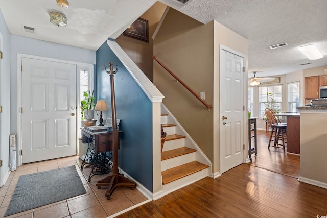 entrance foyer with ceiling fan, a textured ceiling, and light hardwood / wood-style flooring