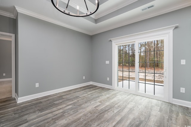 spare room featuring hardwood / wood-style flooring, an inviting chandelier, and ornamental molding