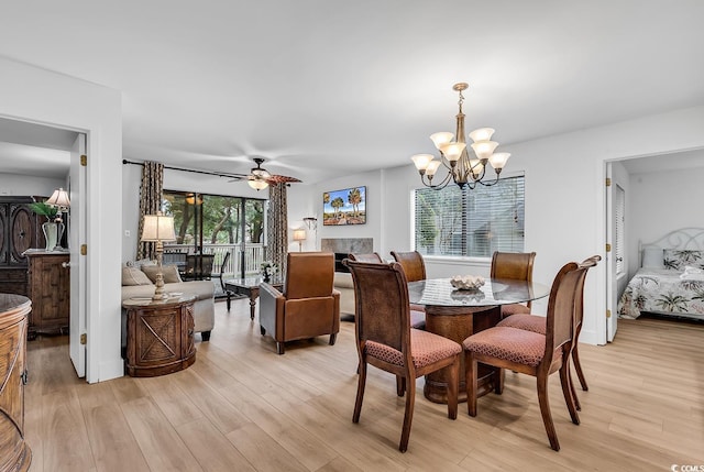 dining space with ceiling fan with notable chandelier and light wood-type flooring