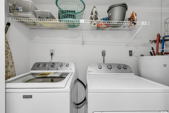 clothes washing area with washing machine and dryer and a textured ceiling