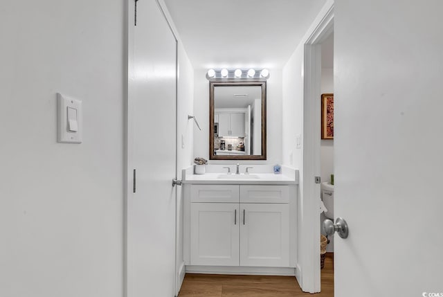 bathroom with hardwood / wood-style floors, vanity, and toilet