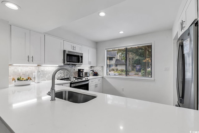 kitchen featuring white cabinets, stainless steel appliances, tasteful backsplash, and sink