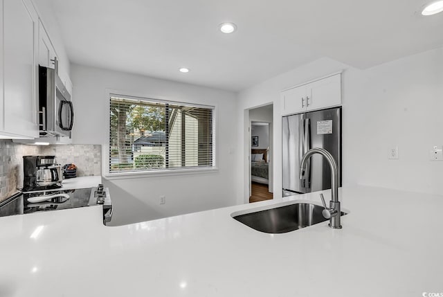 kitchen featuring tasteful backsplash, sink, white cabinets, and appliances with stainless steel finishes