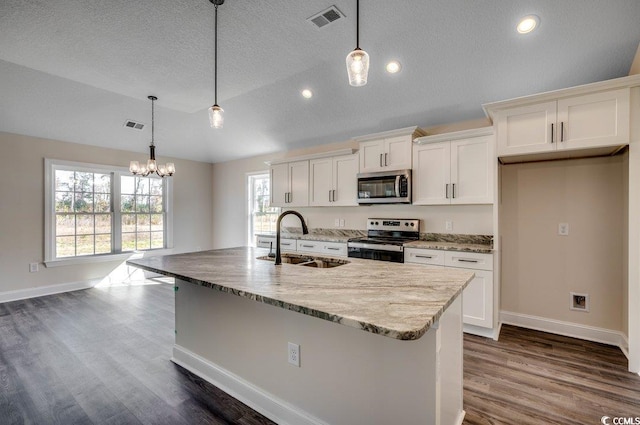 kitchen featuring appliances with stainless steel finishes, sink, pendant lighting, a center island with sink, and dark hardwood / wood-style floors