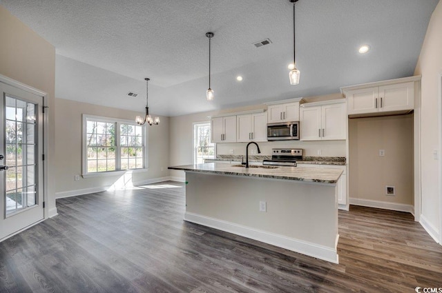 kitchen featuring pendant lighting, dark hardwood / wood-style floors, light stone countertops, appliances with stainless steel finishes, and white cabinetry