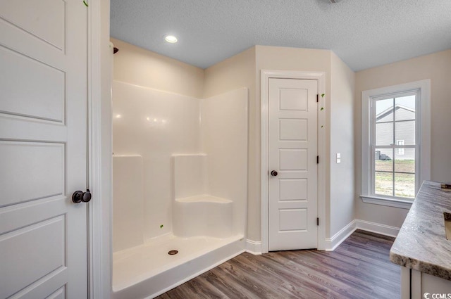 bathroom featuring hardwood / wood-style floors, vanity, a textured ceiling, and walk in shower