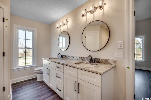 bathroom featuring vanity, a textured ceiling, hardwood / wood-style flooring, and toilet