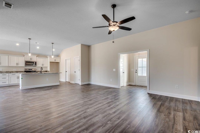 unfurnished living room featuring ceiling fan, dark hardwood / wood-style flooring, and a textured ceiling