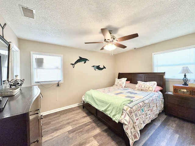 bedroom featuring a textured ceiling, dark hardwood / wood-style flooring, multiple windows, and ceiling fan