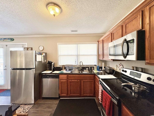 kitchen featuring a textured ceiling, ornamental molding, dark hardwood / wood-style floors, and appliances with stainless steel finishes