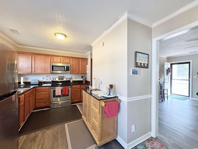 kitchen with a textured ceiling, stainless steel appliances, dark hardwood / wood-style floors, and ornamental molding