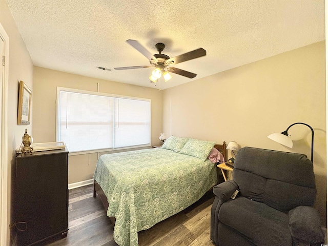 bedroom featuring ceiling fan, dark hardwood / wood-style flooring, and a textured ceiling