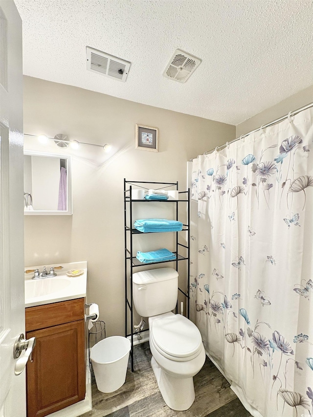 bathroom with wood-type flooring, vanity, a textured ceiling, and toilet