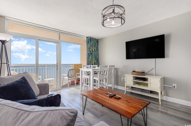 living room with hardwood / wood-style flooring, a notable chandelier, a water view, and a textured ceiling