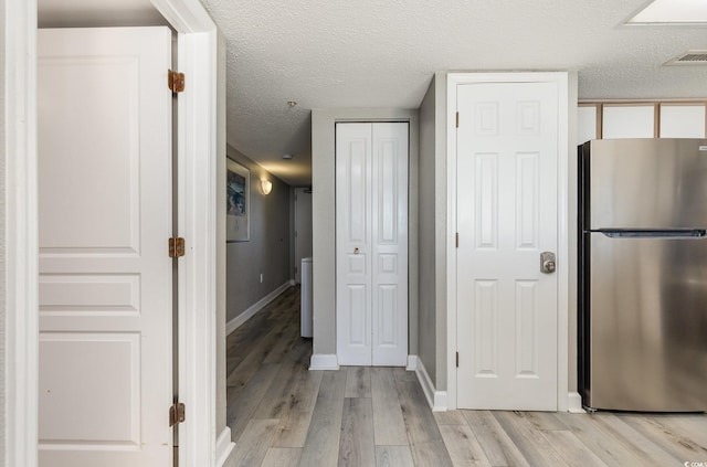 kitchen featuring light hardwood / wood-style floors, a textured ceiling, and stainless steel refrigerator