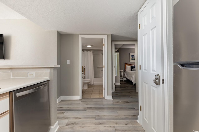 kitchen featuring white cabinets, stainless steel dishwasher, a textured ceiling, and light hardwood / wood-style floors