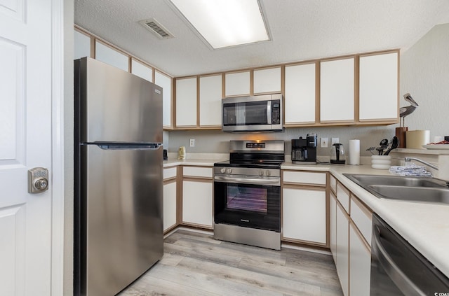 2701 S Ocean Blvd Unit 1808, North Myrtle Beach, SC 29582 - kitchen with appliances with stainless steel finishes, light wood-style floors, light countertops, white cabinetry, and a textured ceiling