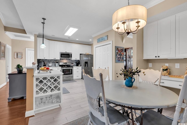 dining room featuring light hardwood / wood-style flooring, a notable chandelier, and crown molding