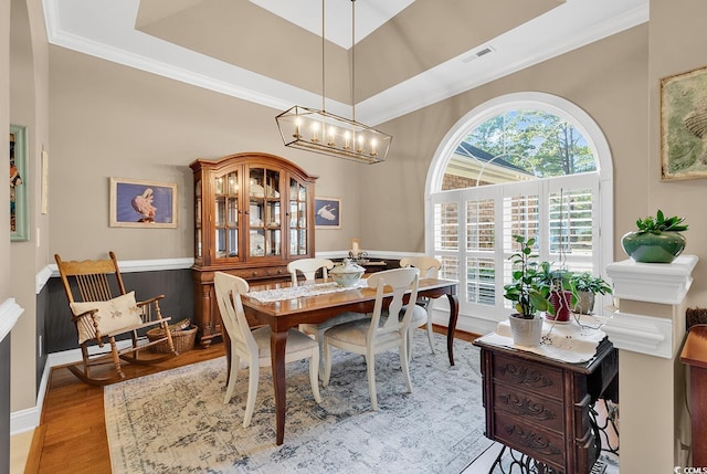 dining area with light hardwood / wood-style floors, crown molding, and a notable chandelier