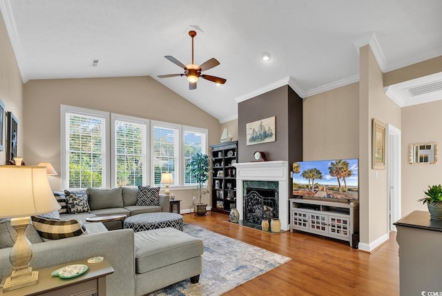 living room with vaulted ceiling, light hardwood / wood-style flooring, ceiling fan, a premium fireplace, and ornamental molding