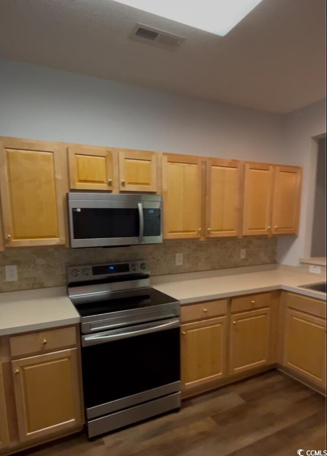 kitchen featuring light brown cabinetry, dark wood-type flooring, and appliances with stainless steel finishes