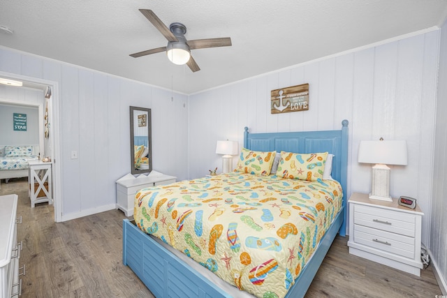 bedroom with hardwood / wood-style flooring, ornamental molding, ceiling fan, and a textured ceiling