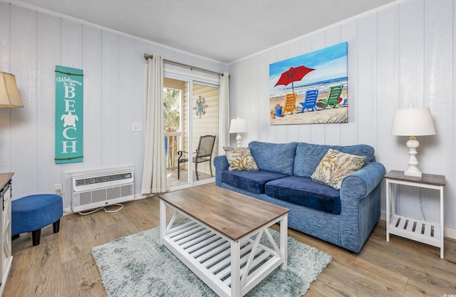 living room featuring hardwood / wood-style flooring, ornamental molding, and a wall mounted AC