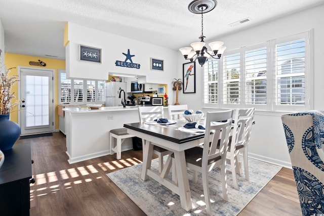 dining area with hardwood / wood-style floors, a healthy amount of sunlight, and a textured ceiling