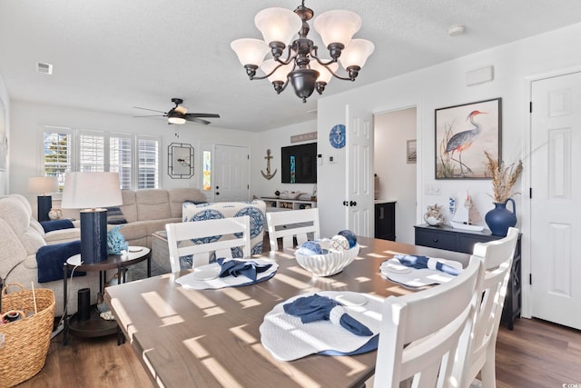 dining space featuring a textured ceiling, ceiling fan with notable chandelier, and dark wood-type flooring