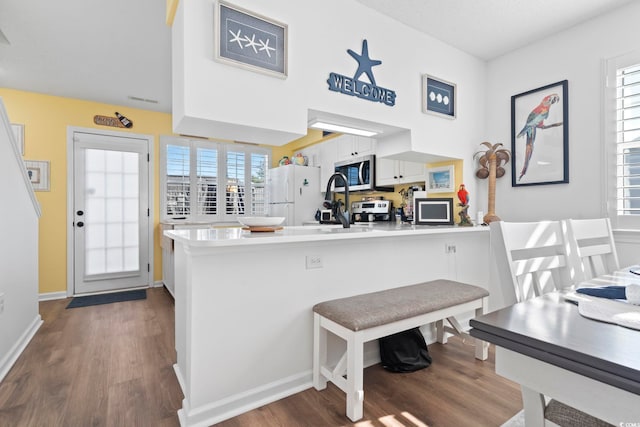 kitchen with white cabinetry, kitchen peninsula, a healthy amount of sunlight, and appliances with stainless steel finishes