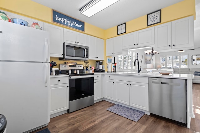 kitchen with sink, kitchen peninsula, dark hardwood / wood-style floors, white cabinetry, and stainless steel appliances