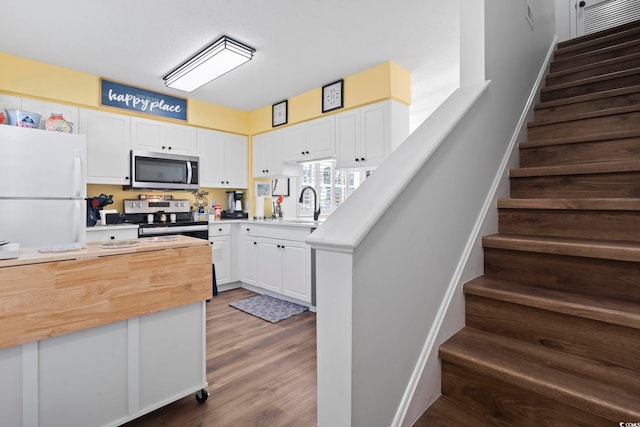 kitchen with wood counters, white cabinets, sink, dark hardwood / wood-style flooring, and stainless steel appliances