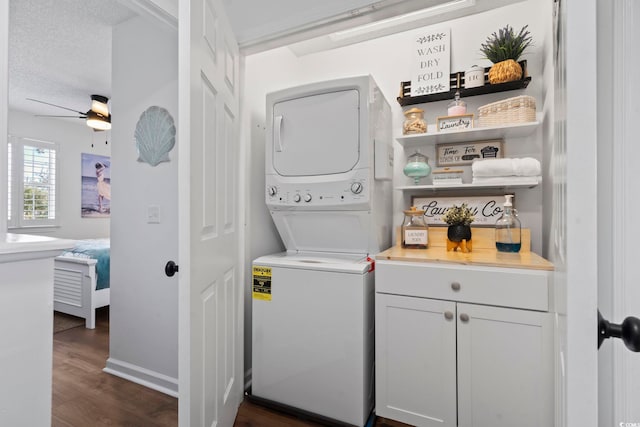 clothes washing area featuring a textured ceiling, stacked washer / dryer, ceiling fan, and dark hardwood / wood-style floors