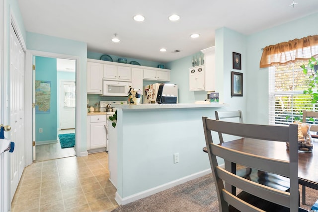 kitchen featuring kitchen peninsula, white cabinetry, and white appliances