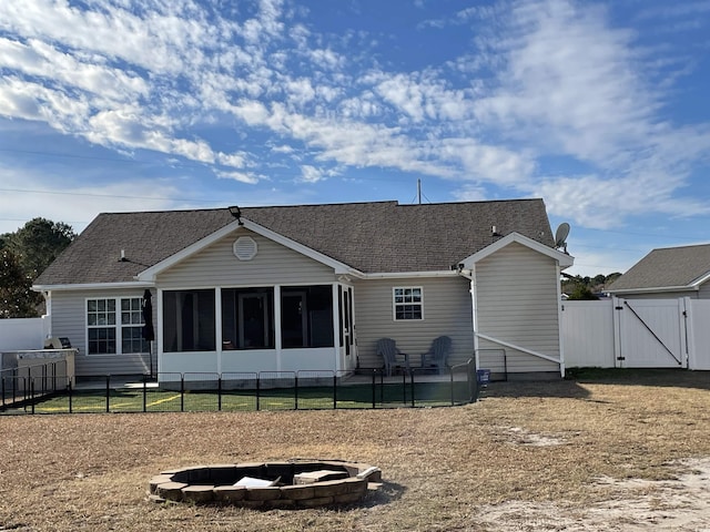 rear view of property with a sunroom and an outdoor fire pit