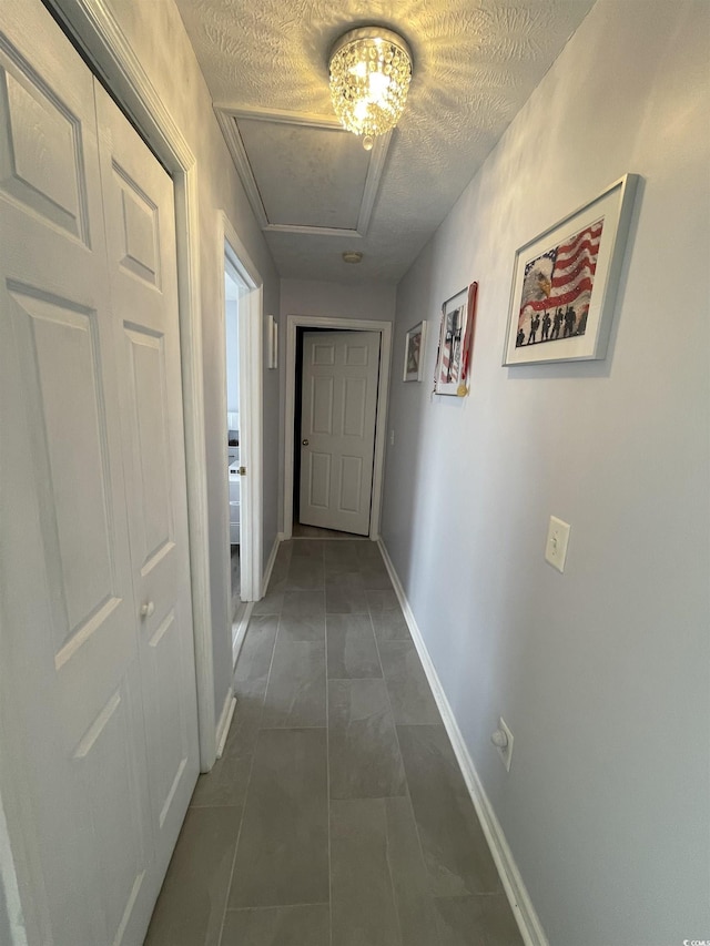 corridor featuring dark tile patterned flooring and a textured ceiling