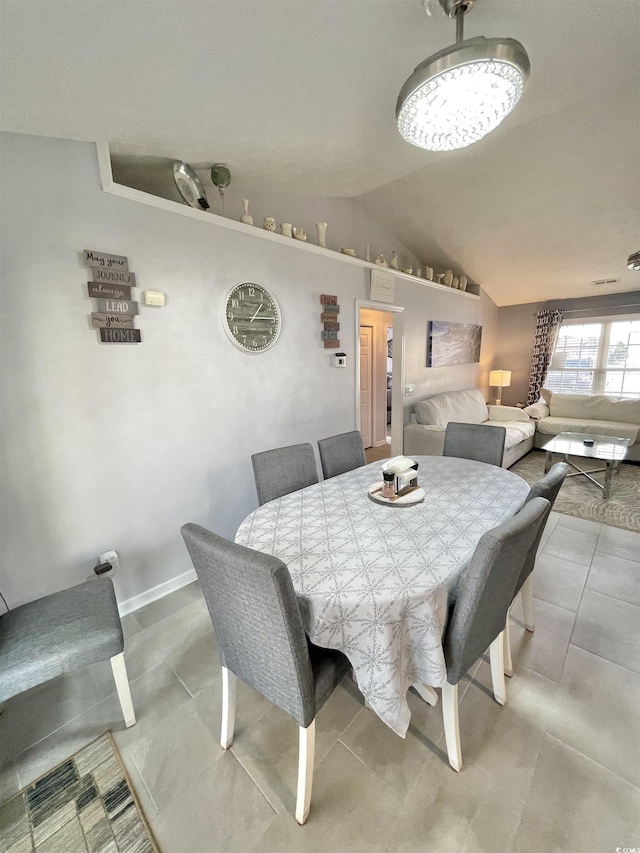 dining room with light tile patterned flooring, lofted ceiling, and an inviting chandelier