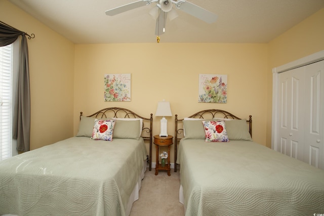 carpeted bedroom featuring ceiling fan and a closet