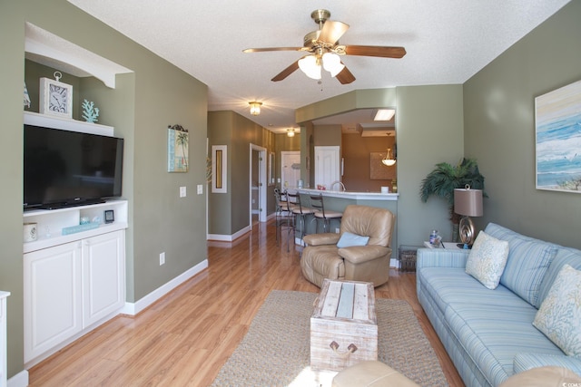 living room featuring a textured ceiling, light hardwood / wood-style flooring, and ceiling fan