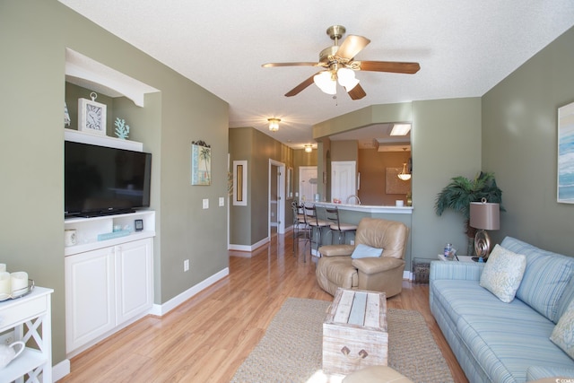 living room with a textured ceiling, light hardwood / wood-style floors, and ceiling fan